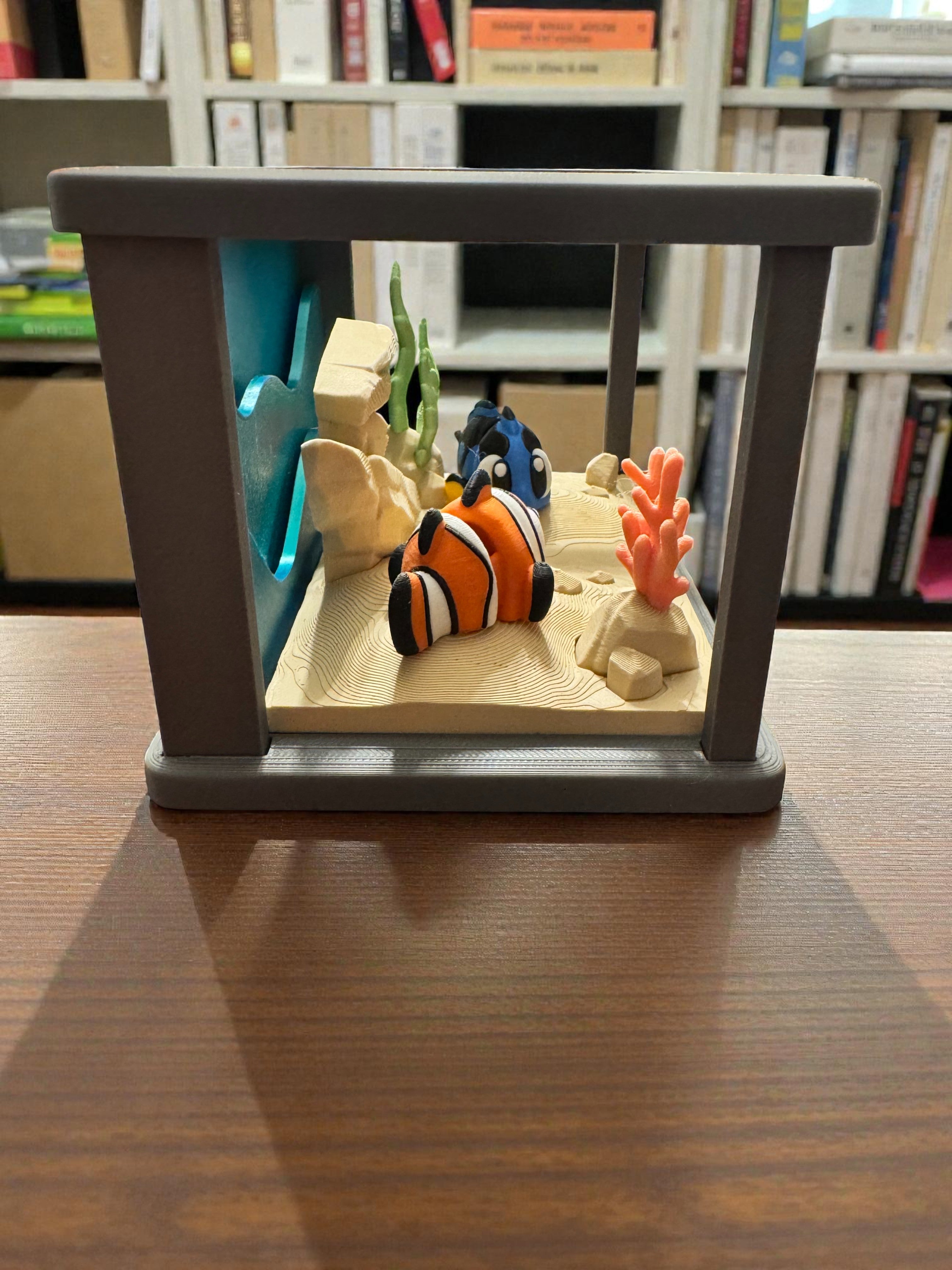 Model aquarium with fish and coral on a wooden surface