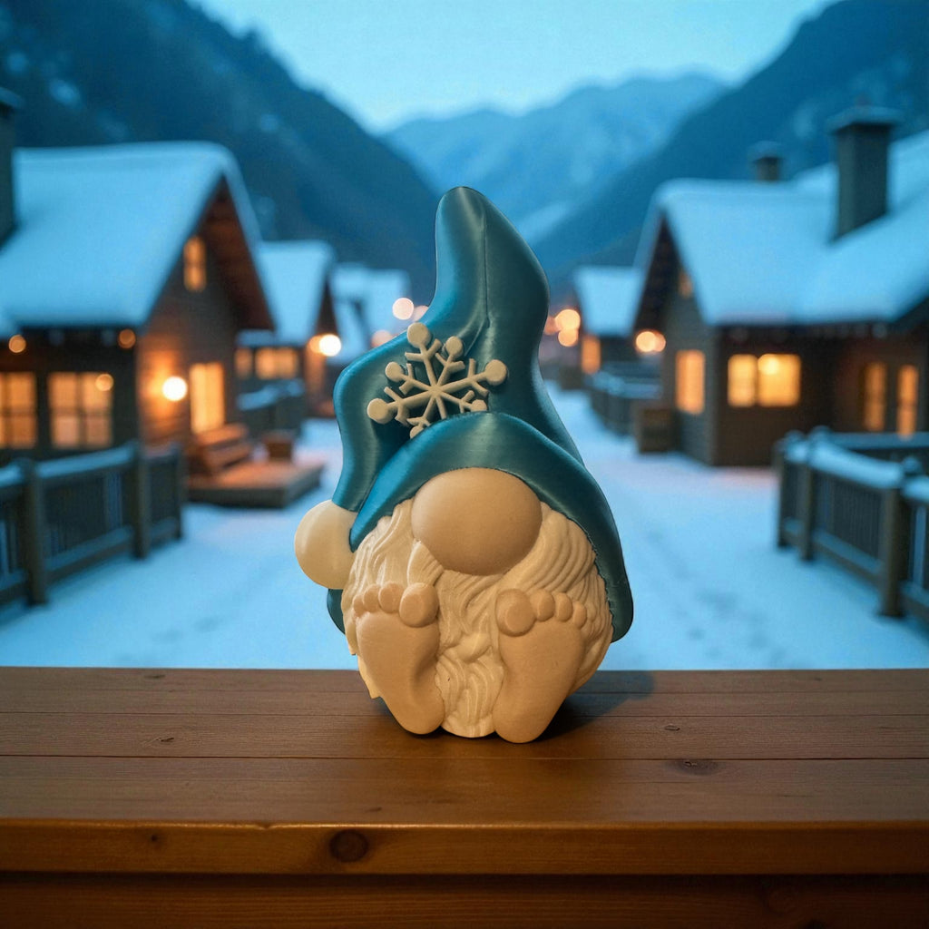 Gnome figurine with a blue hat and snowflake design in front of a snowy mountain village.