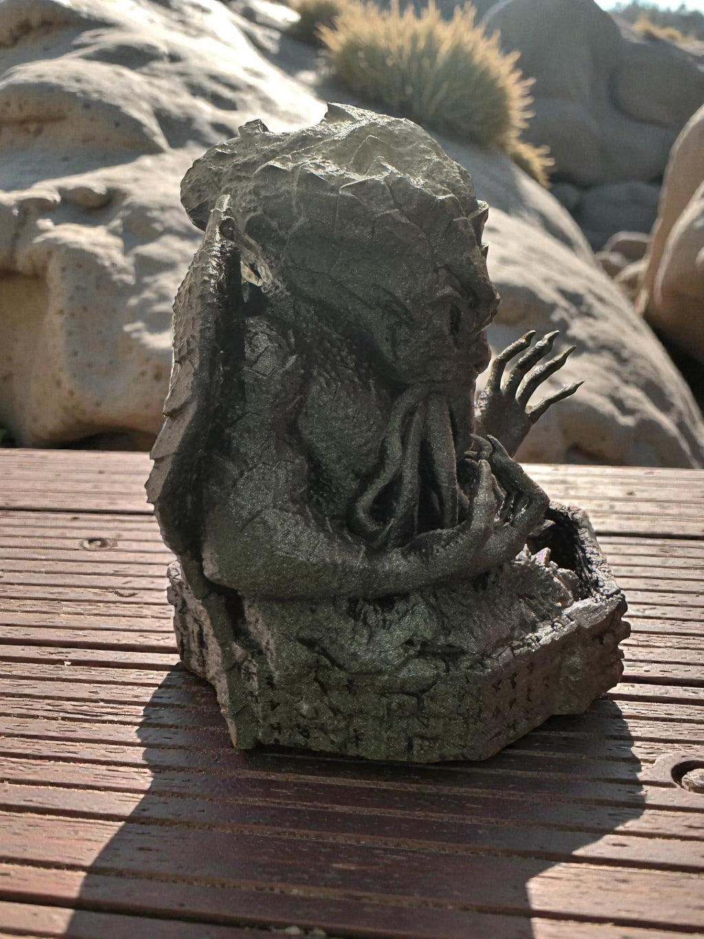 A Cthulhu dice tower facing right on a wooden surface with a natural background
