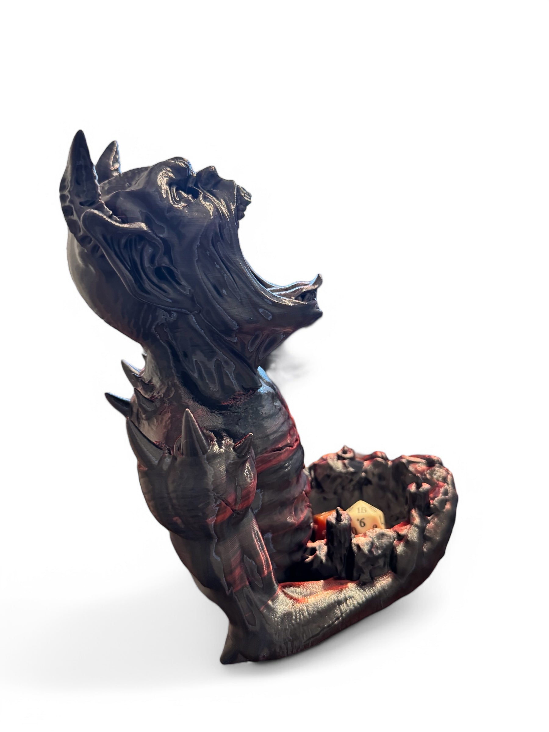 An imp shaped dice tower facing the right side holding some dice on a white background.