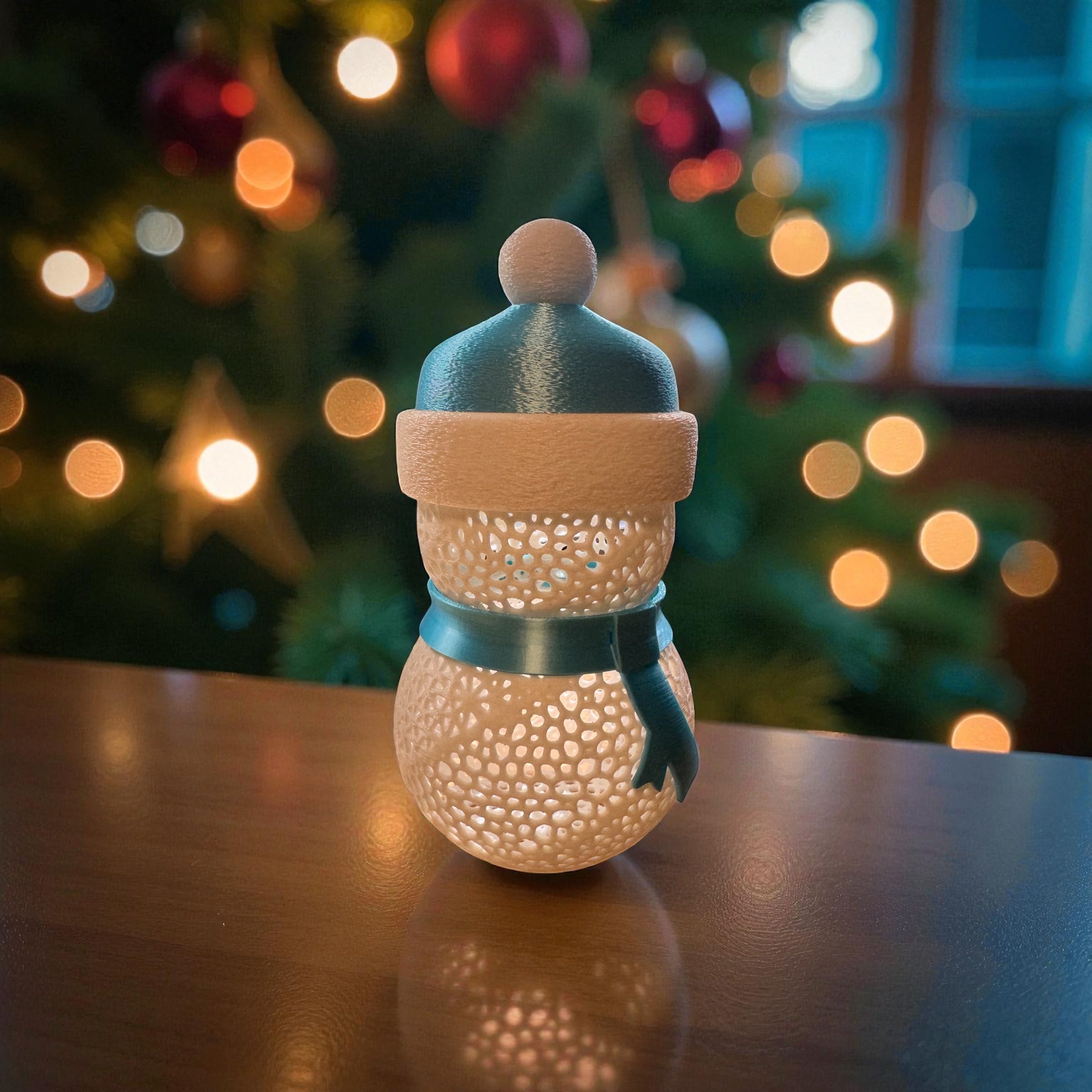 Decorative snowman-shaped lantern with a blurred Christmas tree in the background