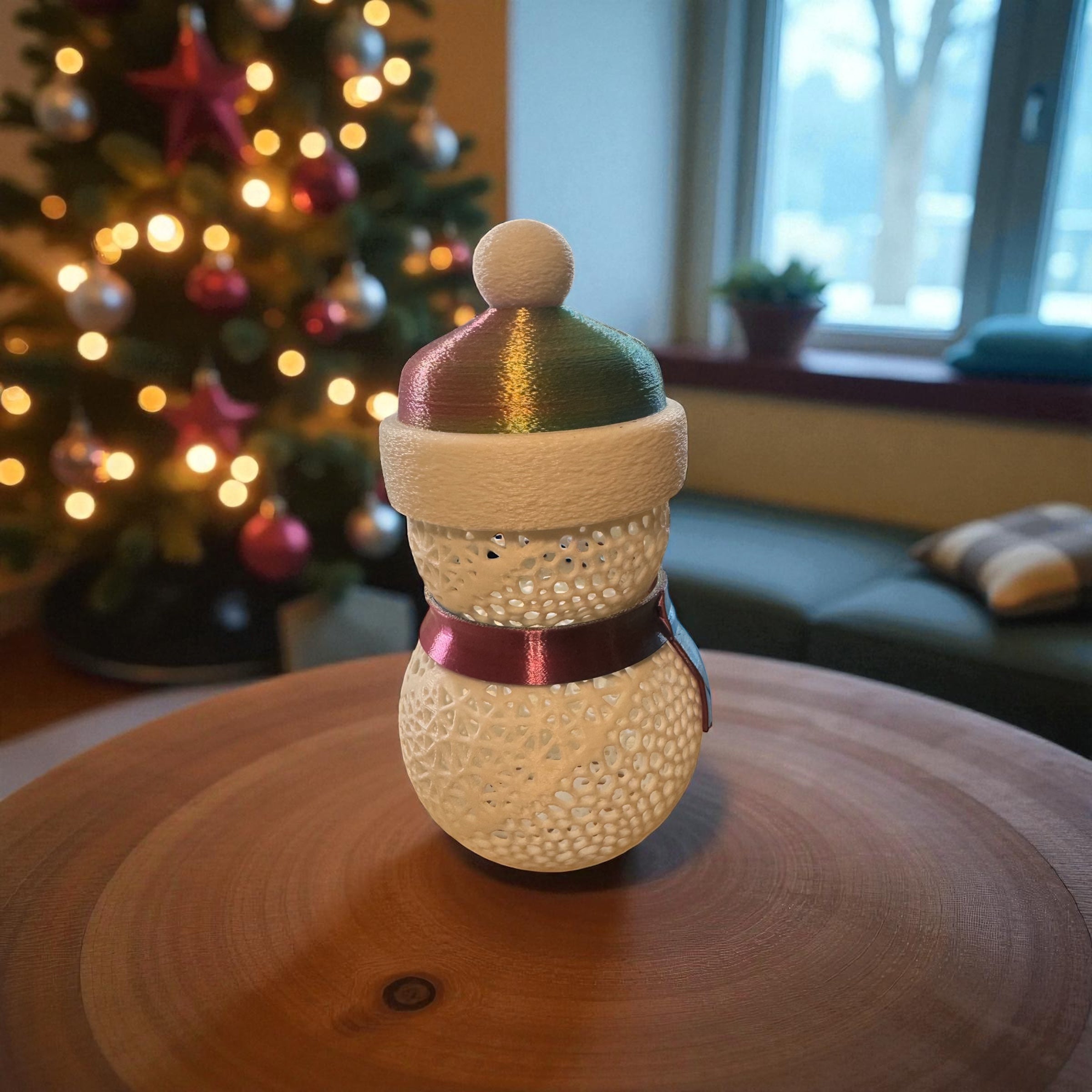 Decorative snowman ornament on a wooden surface with a Christmas tree in the background