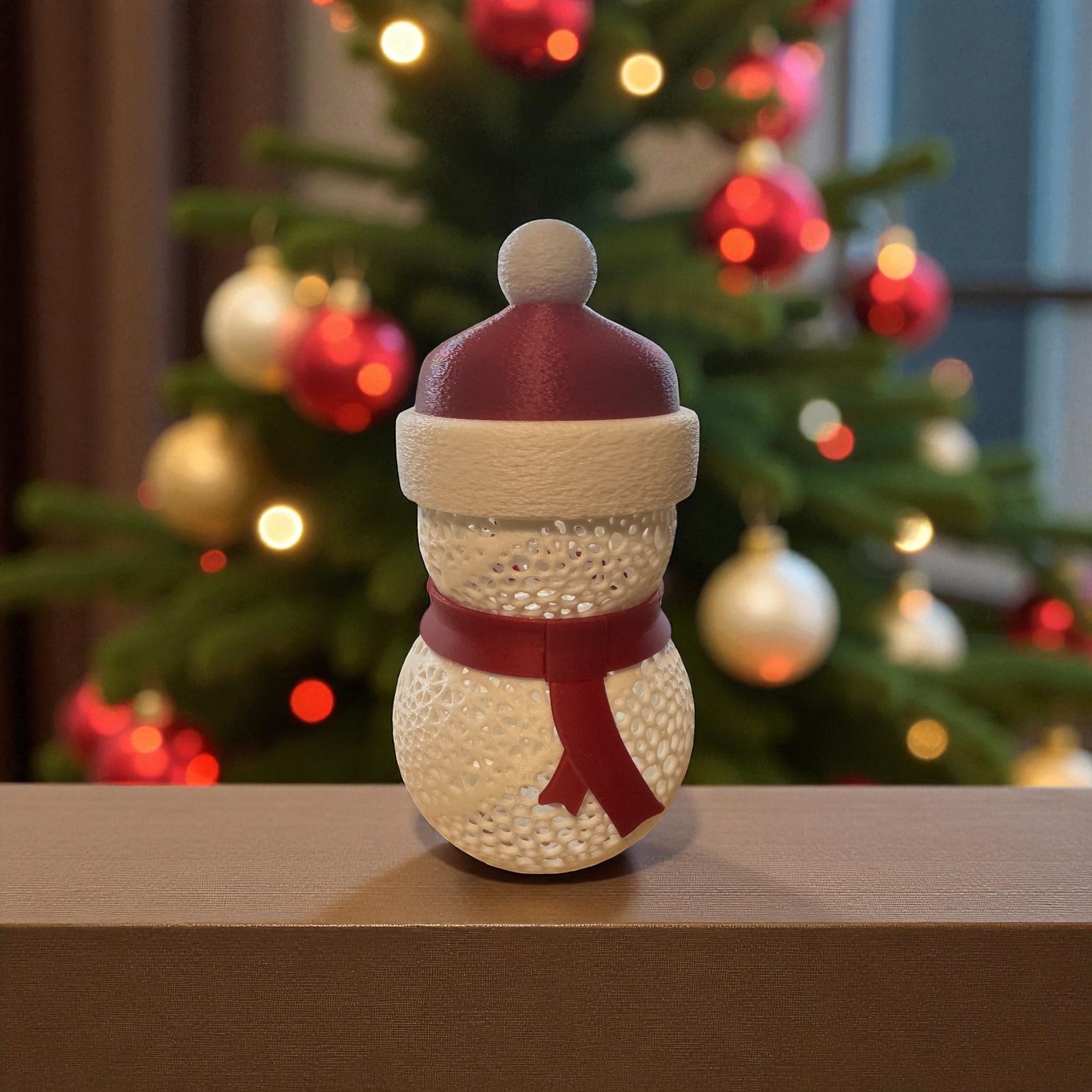Decorative snowman ornament with a red hat and scarf in front of a Christmas tree.