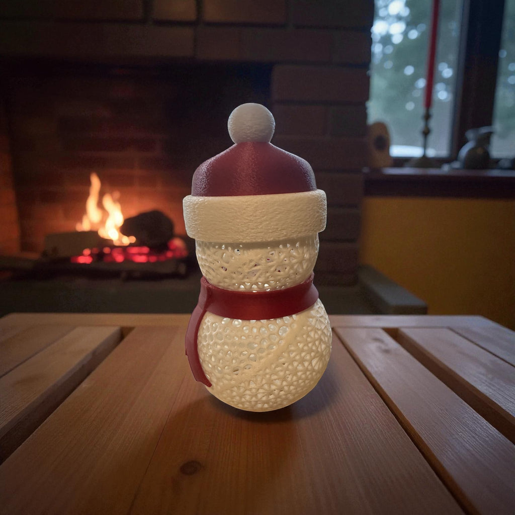 Decorative snowman ornament with a red hat and scarf on a wooden table in front of a fireplace.