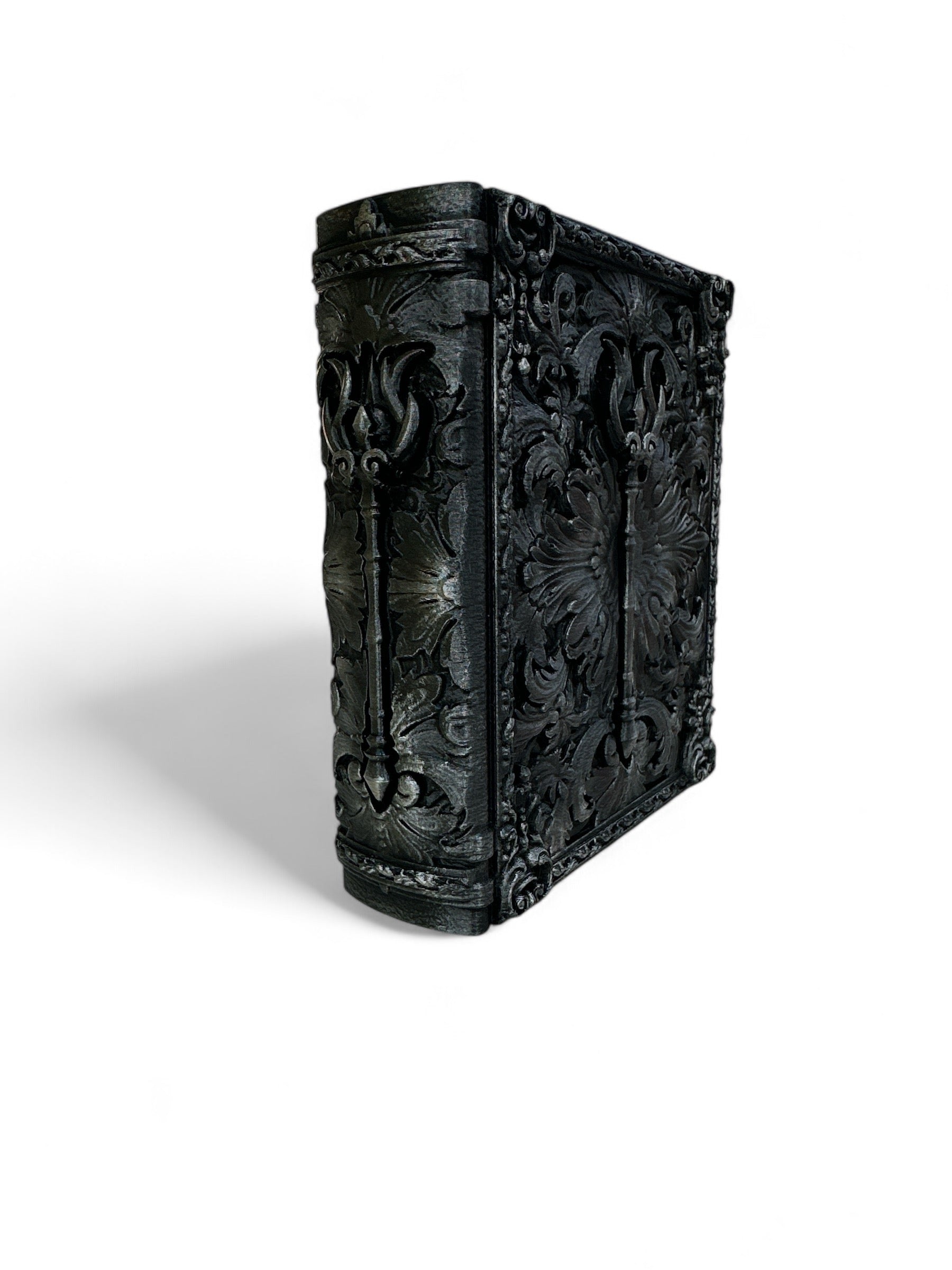 A black storage container designed to resemble a tome with intricate carvings and a fantasy-themed cover.