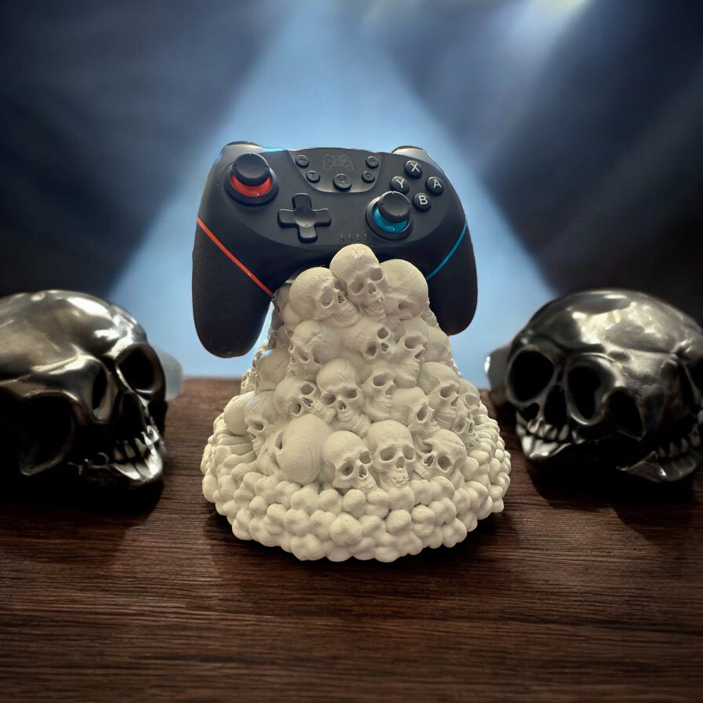 Gaming controller on a skull-shaped stand with two skulls on either side, against a dark background.