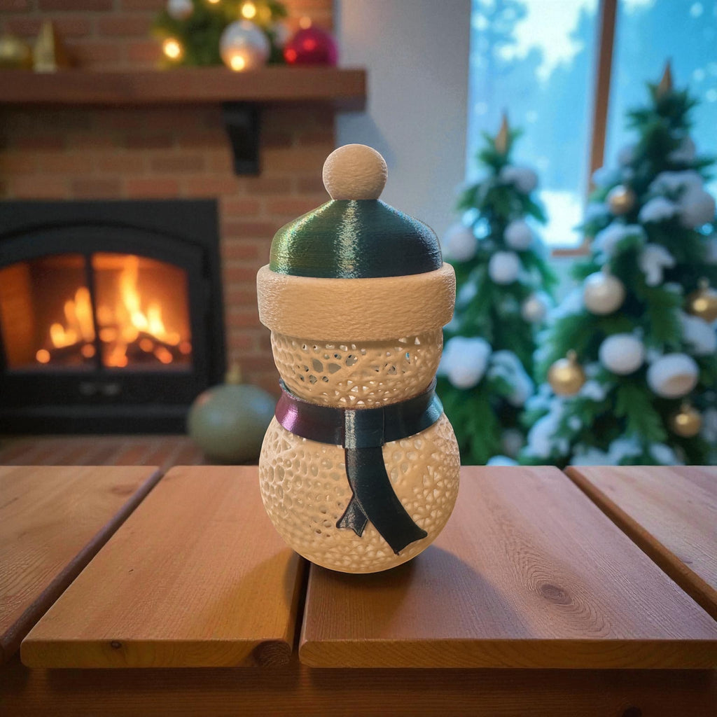 Decorative snowman ornament on a wooden table with a fireplace and Christmas tree in the background.